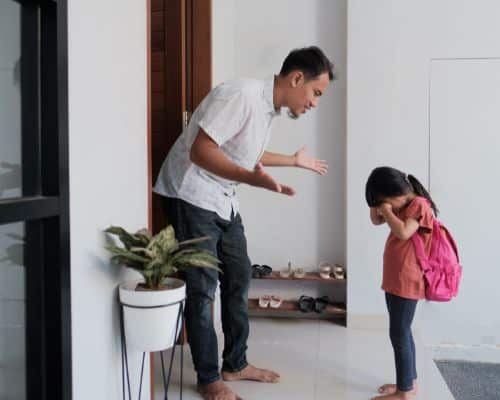 A father yelling at his young daughter while she hangs her head in fear and shame, representing the concept of will narcissists hurt their children.