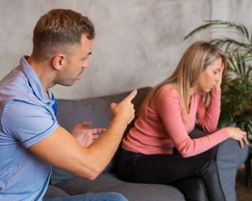 A couple sitting on opposite ends of a sofa. The man is chastising his wife while she is turned away, looking defeated and too tired to fight for herself. The title of the article is "Covert Narcissist Checklist: Help to Find the Truth."