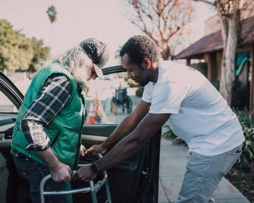 A man helping another disabled man get out of his car and use his walker. This represents when a narcissist does things to make others think he is a good person. The name of the article is "Covert Narcissist Checklist: Help to Find the Truth."