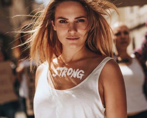 A woman looking strong and beautiful, long hair blowing in the breeze, with the word "strong" written across her upper chest. This photo represents the article, Surviving a Narcissist: It's Easier than you Think!"
